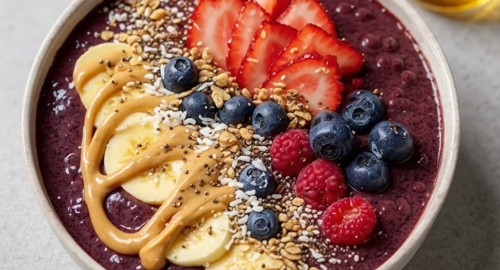 Easy Acai Bowl Recipe topped with fresh fruits, crunchy granola, and creamy peanut butter drizzle.